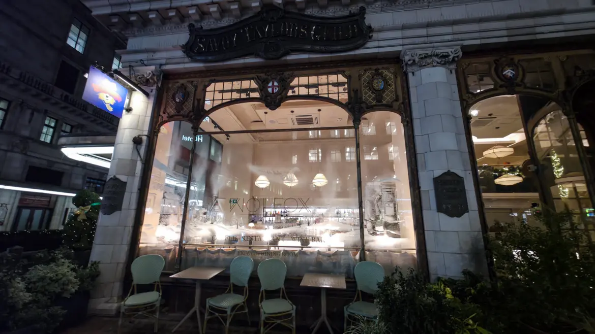 Wolfox Savoy's lit frontage under the engraved Savoy Taylors Guild sign, corner of Savoy Court and the Strand, London.