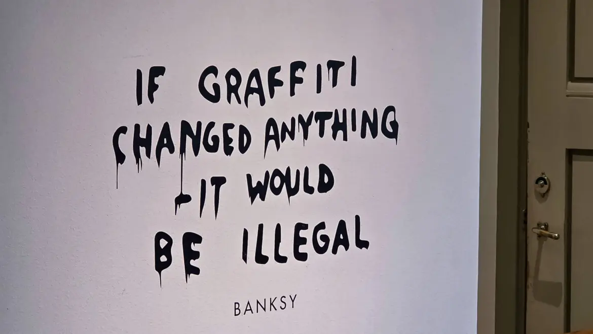 A wall at the Moco Museum painted with Banksy’s line “if graffiti changed anything it would be illegal” in dripping black letters, his name printed beneath