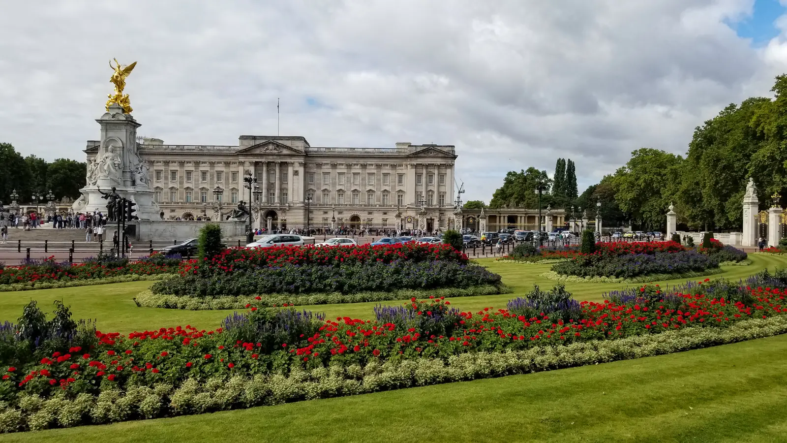 Buckingham Palace behind its flower gardens, with the gilded Victoria Memorial to the left, in central London