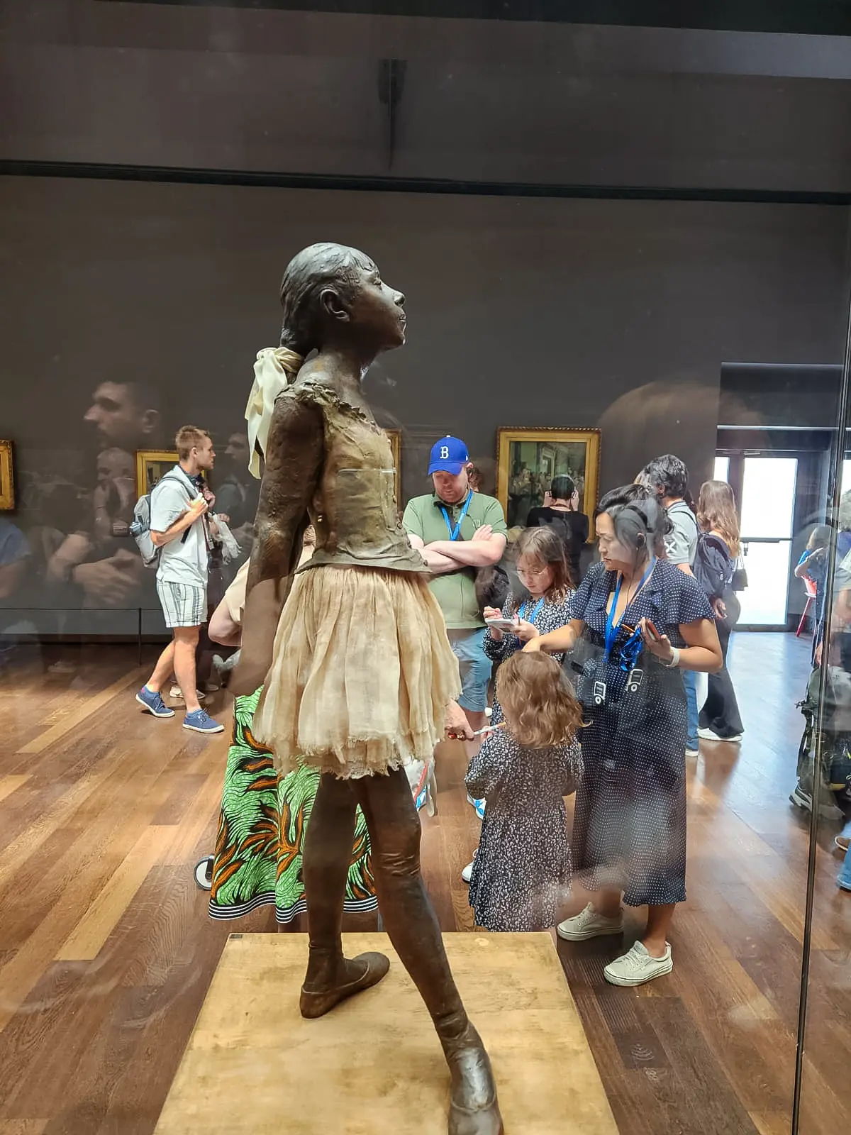 Degas’s Little Dancer Aged Fourteen in her glass case at the Musée d’Orsay, in a fabric tutu with her chin raised and hands behind her back