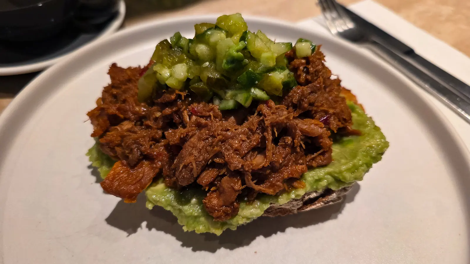 Spicy pulled chicken at Flow, piled on smashed avocado on sourdough, topped with a bright green chopped cucumber salad