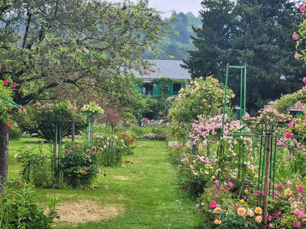 Rose arches and flower beds in the Clos Normand at Giverny, with Monet’s pink house and green shutters at the end of the path