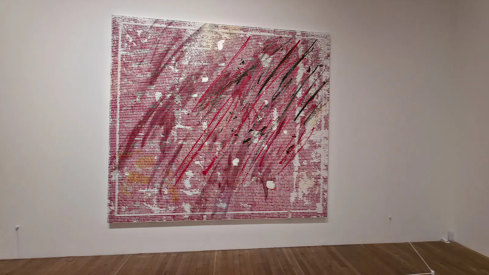 Jacqueline Humphries’s red-and-white canvas of character rows crossed by pink and black strokes, 2018, at Tate Modern, London