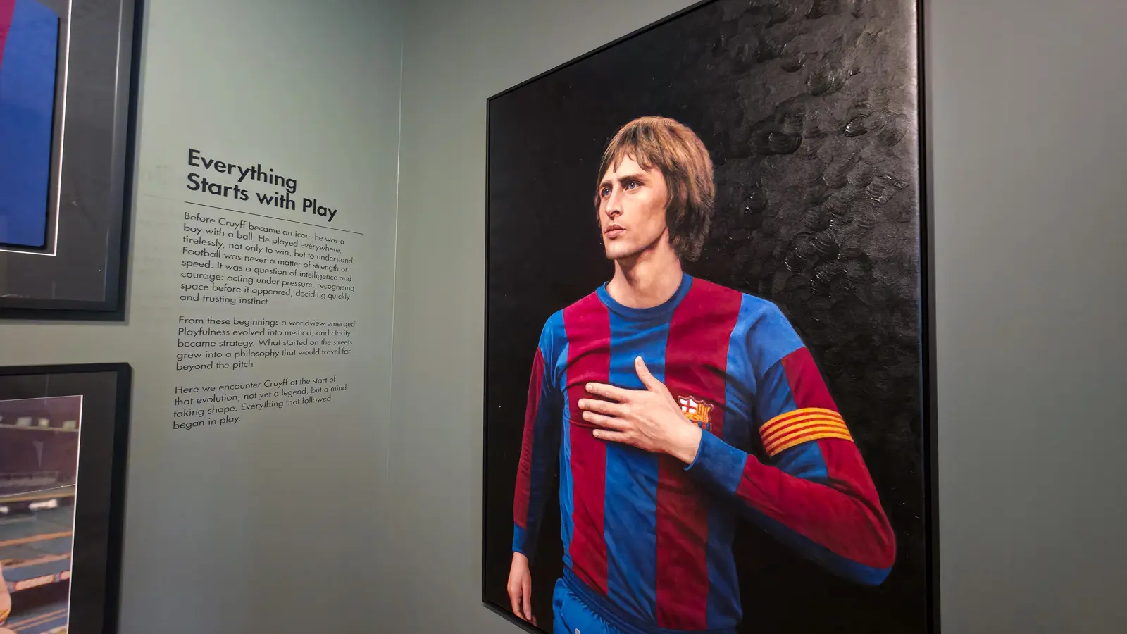 A painted portrait of Johan Cruyff in the Barcelona shirt beside the Everything Starts with Play wall panel at the Moco Museum