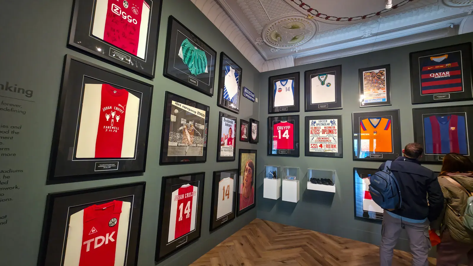 The Johan Cruyff exhibition room at the Moco Museum, framed shirts on two walls with the blue Akkerstraat street sign among them