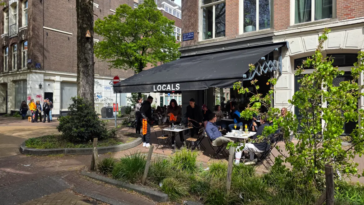 The LOCALS awning and pavement terrace on the corner of Eerste Jacob van Campenstraat in De Pijp, Amsterdam, with King’s Day orange at the tables
