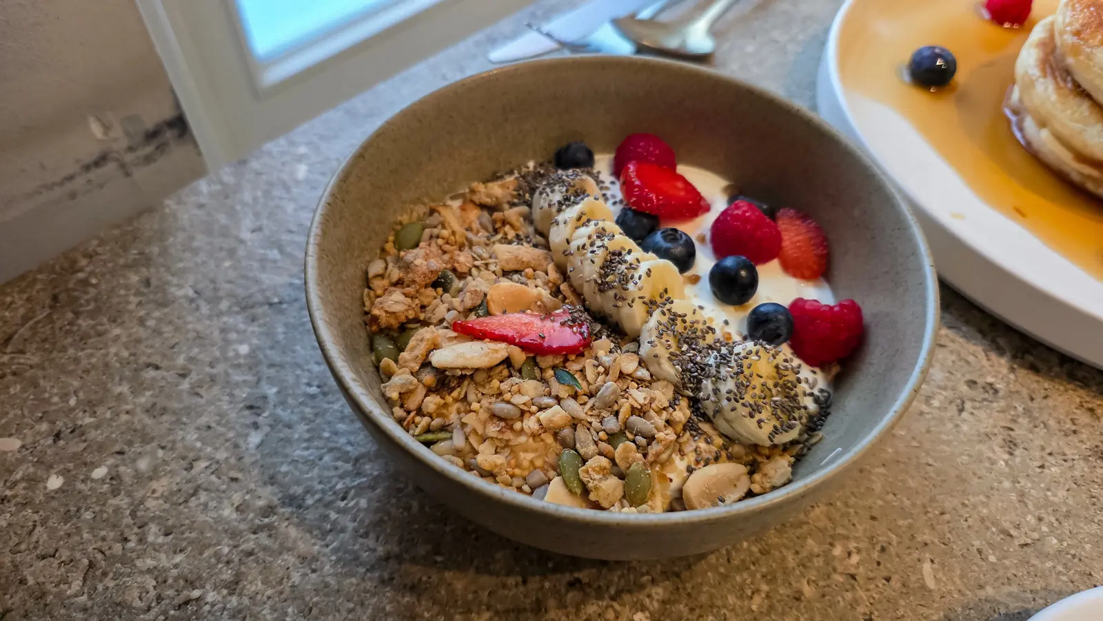Greek yoghurt bowl at Locals Amsterdam with home-made granola, sliced banana, berries and chia seeds
