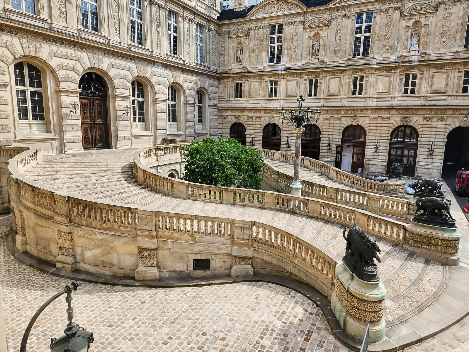 The double horseshoe ramp in the Cour Lefuel at the Louvre, with balustrades, bronze animals on the piers and a lamp column at the centre