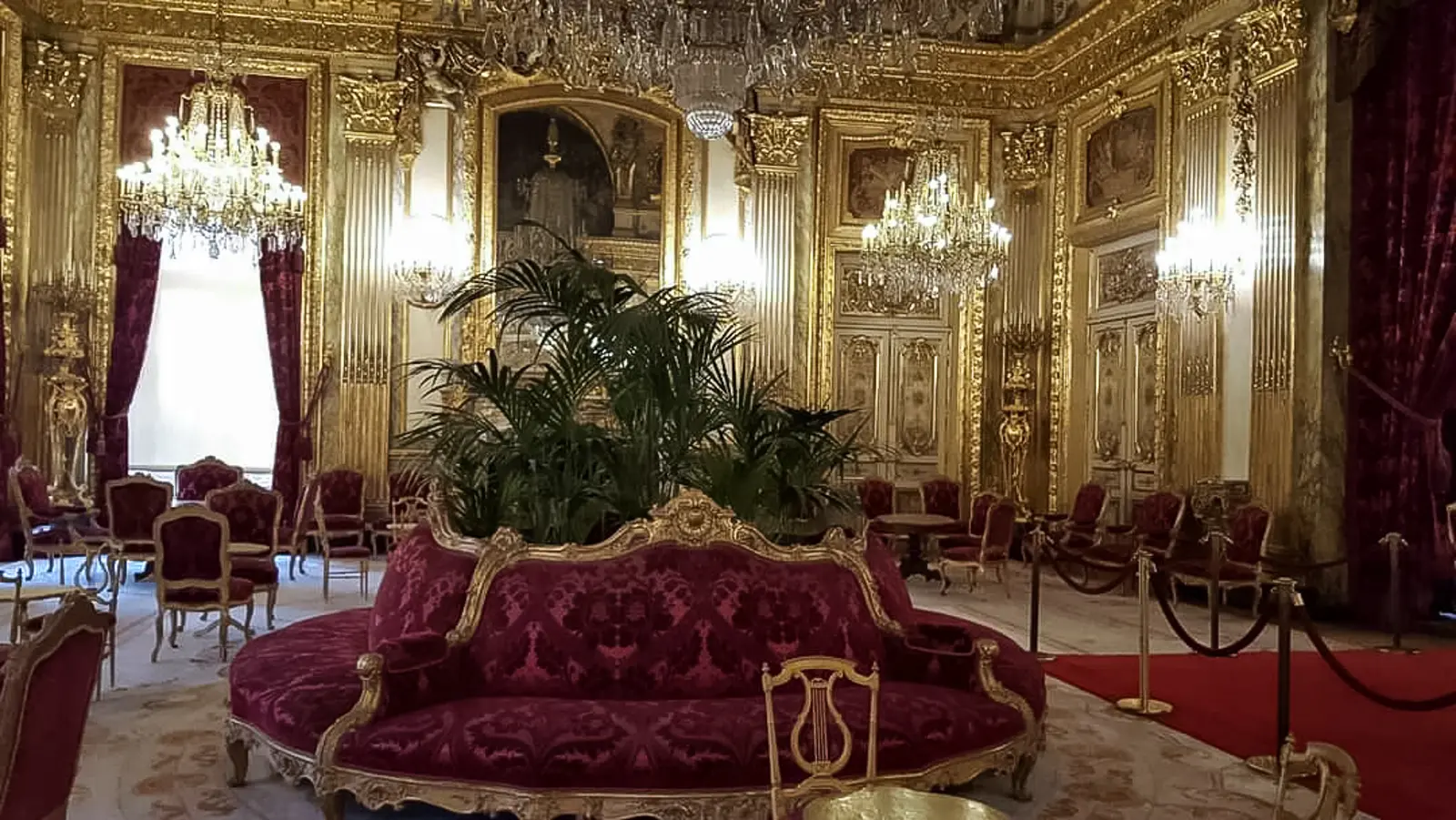 The Grand Salon of the Napoleon III Apartments at the Louvre, with gilded panelling, crystal chandeliers and a curved crimson sofa