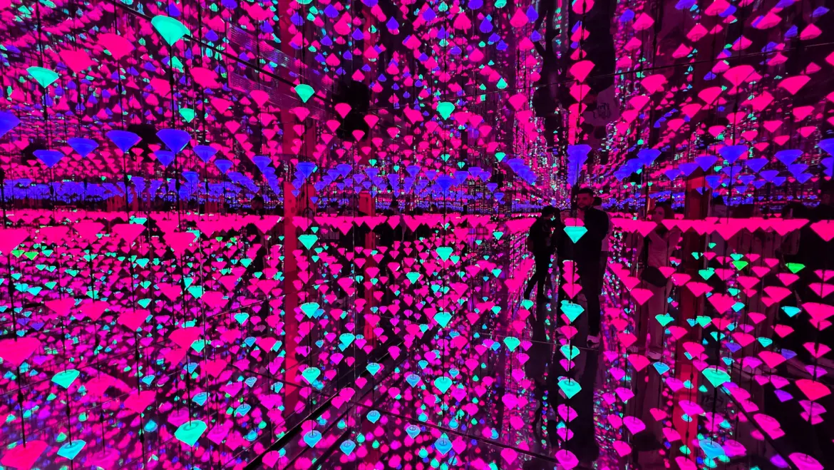 Studio Irma’s Diamond Matrix at Moco Museum Amsterdam, a mirrored room hung with glowing pink, blue and teal diamonds repeating in all directions