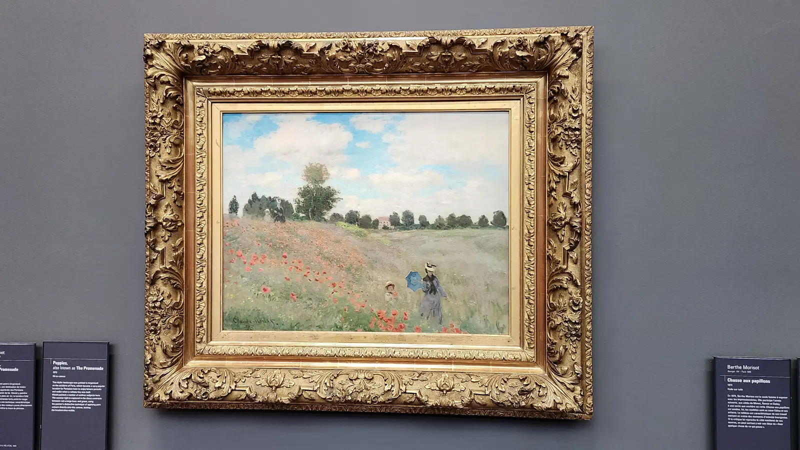 Monet’s Poppies in an ornate gilt frame at the Musée d’Orsay, a field of red flowers with a woman and child walking through it