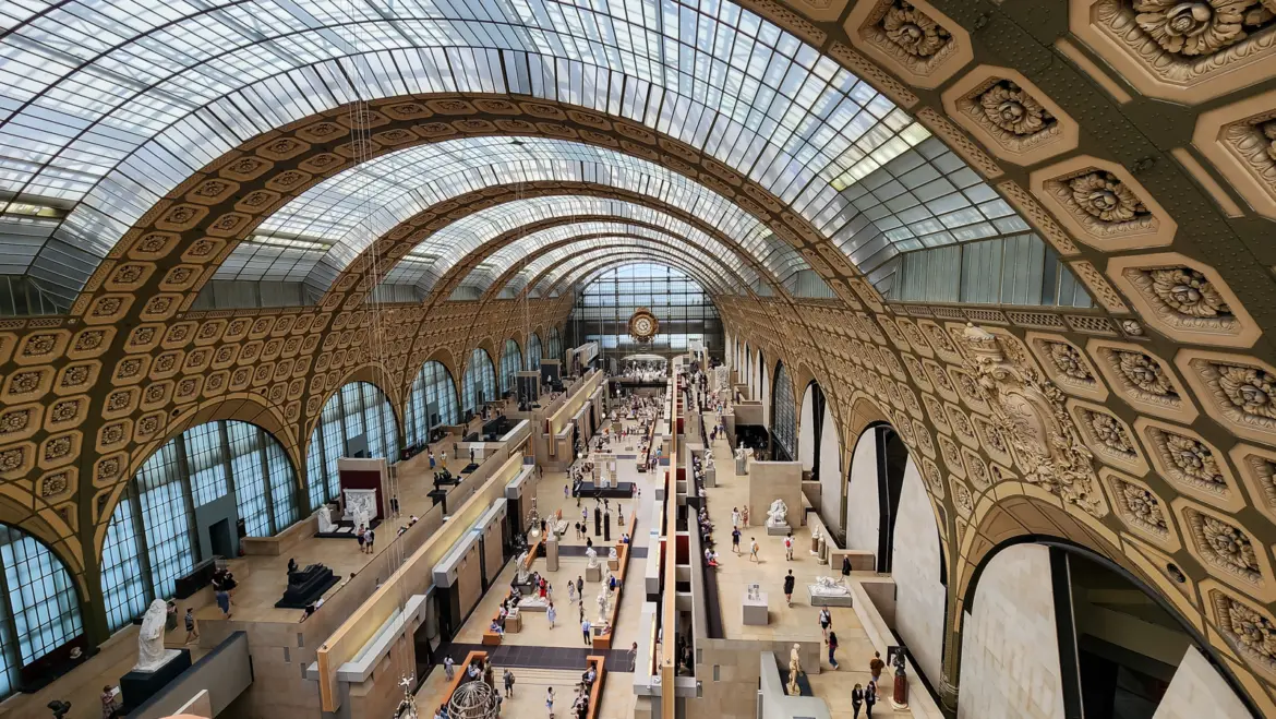 The great hall of the Musée d’Orsay from above, a glazed barrel vault over galleries and sculpture, with the station clock at the far end
