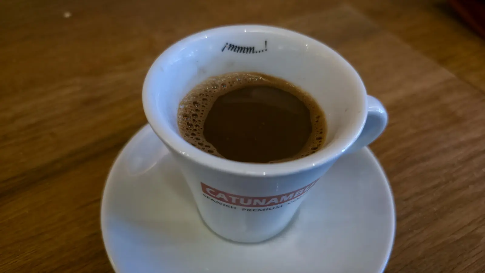 A small cup of Greek coffee at Oresti’s Taverna in a white cup branded Catunambu, Spanish Premium, on a saucer