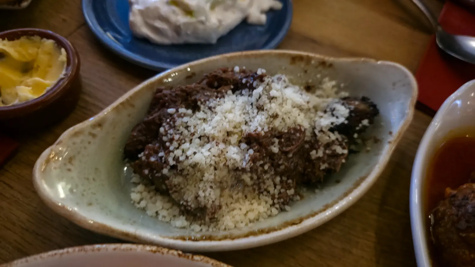A dish of slow-cooked beef stew at Oresti’s Taverna, dark with tomato and topped with grated cheese