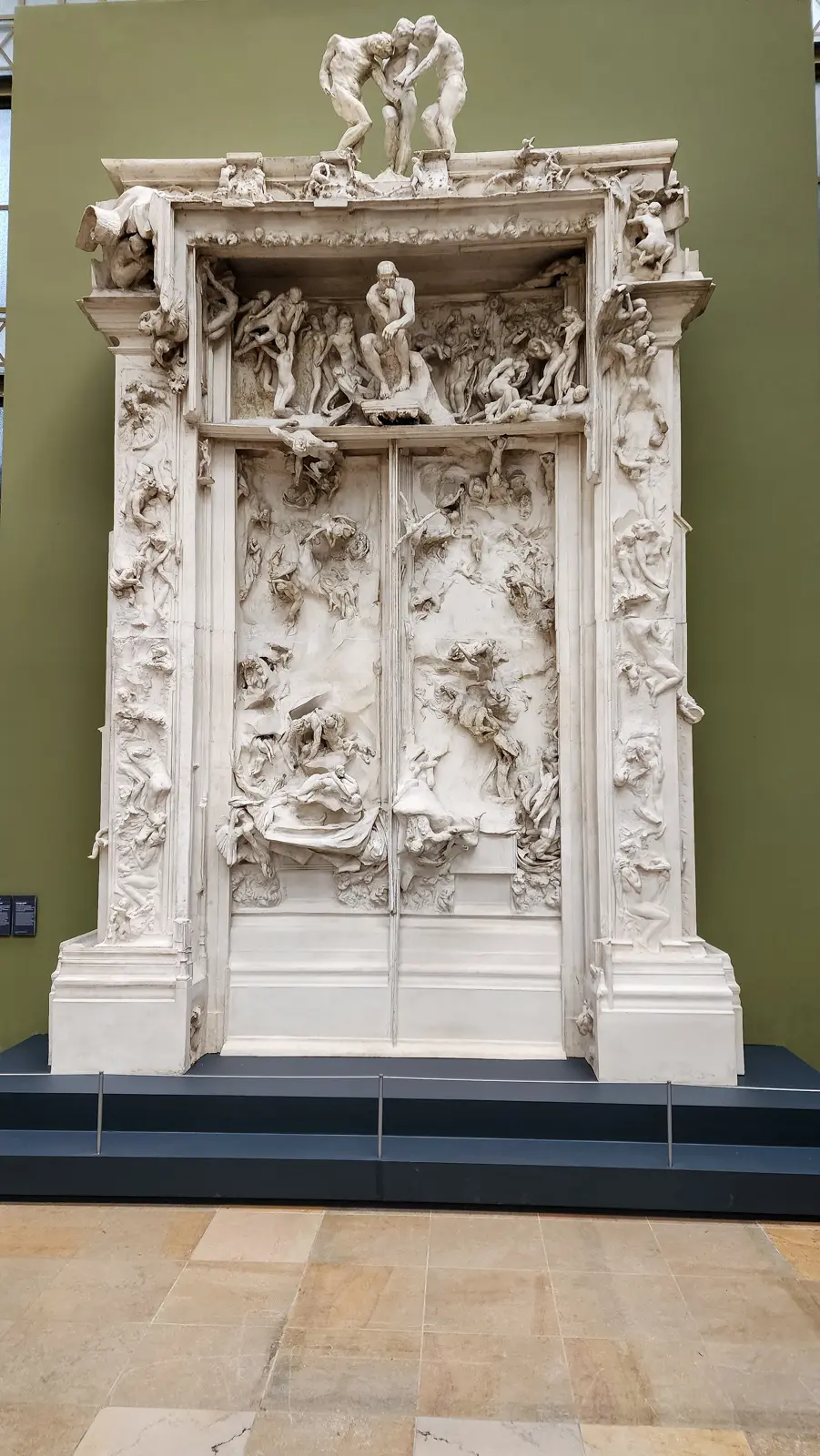 Rodin’s plaster Gates of Hell at the Musée d’Orsay, a towering white portal crowded with writhing figures, set against an olive green wall