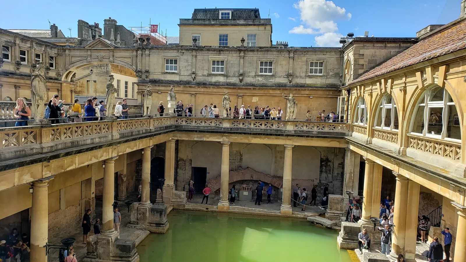 The Great Bath at the Roman Baths in Bath, green thermal water below a stone terrace lined with statues, a day trip from London