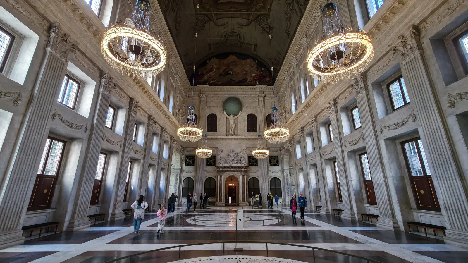 The Burgerzaal or Citizens’ Hall inside the Royal Palace Amsterdam, a vast marble hall with ring chandeliers and a barrel-vaulted ceiling