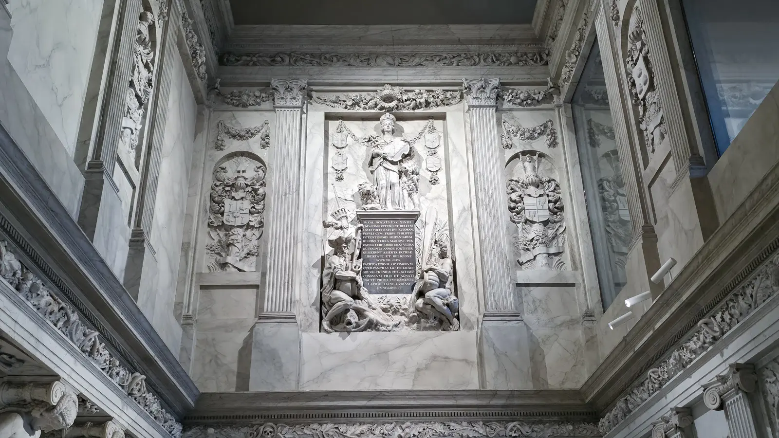 Carved coats of arms in arched niches in the Vierschaar, Royal Palace Amsterdam, beneath a skull-and-foliage frieze