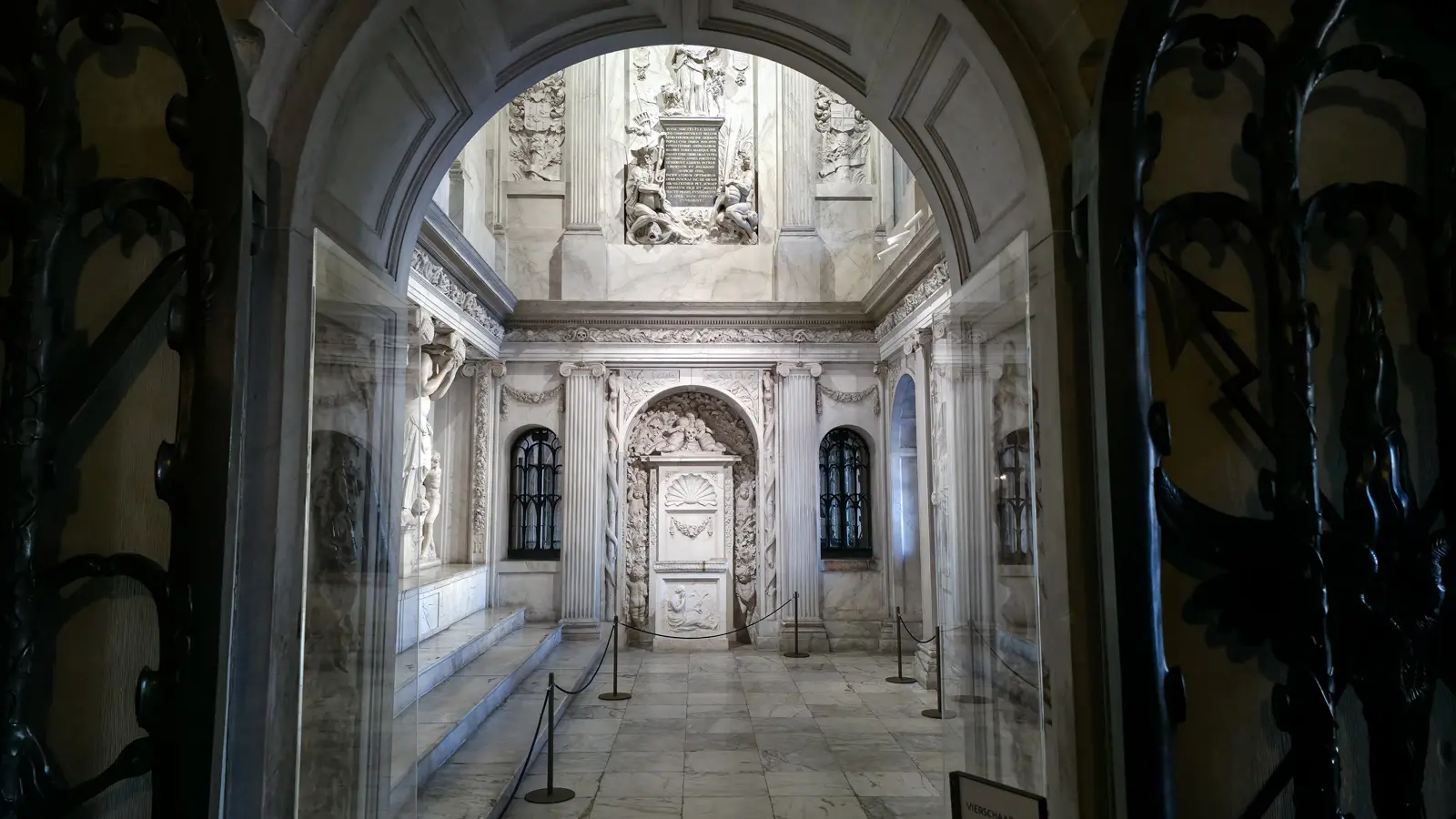 View into the marble Vierschaar of the Royal Palace Amsterdam through the carved arched entrance, with rope barriers on the floor