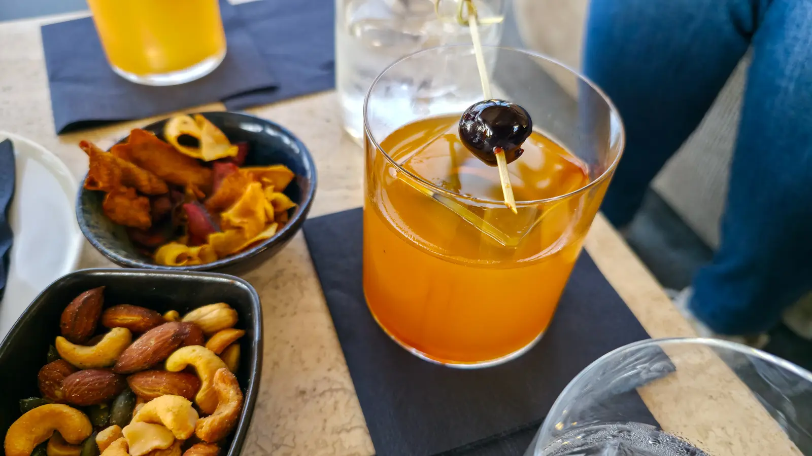 The Amber Horizon at the W Lounge, W Amsterdam, an amber cocktail in a tumbler with a dark cherry on a wooden skewer
