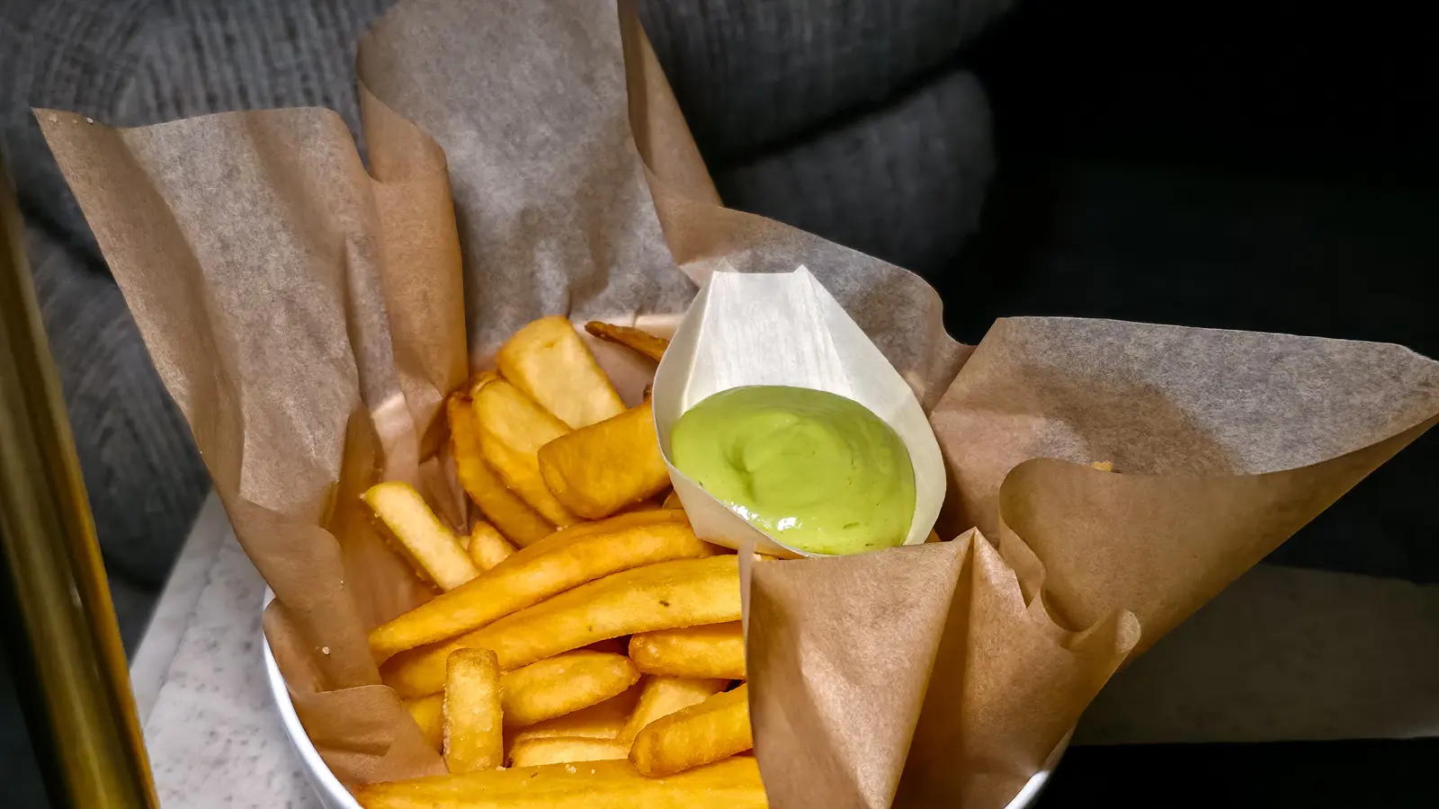 A paper-lined bowl of fries with a cone of pale green basil aioli at the W Lounge, W Amsterdam