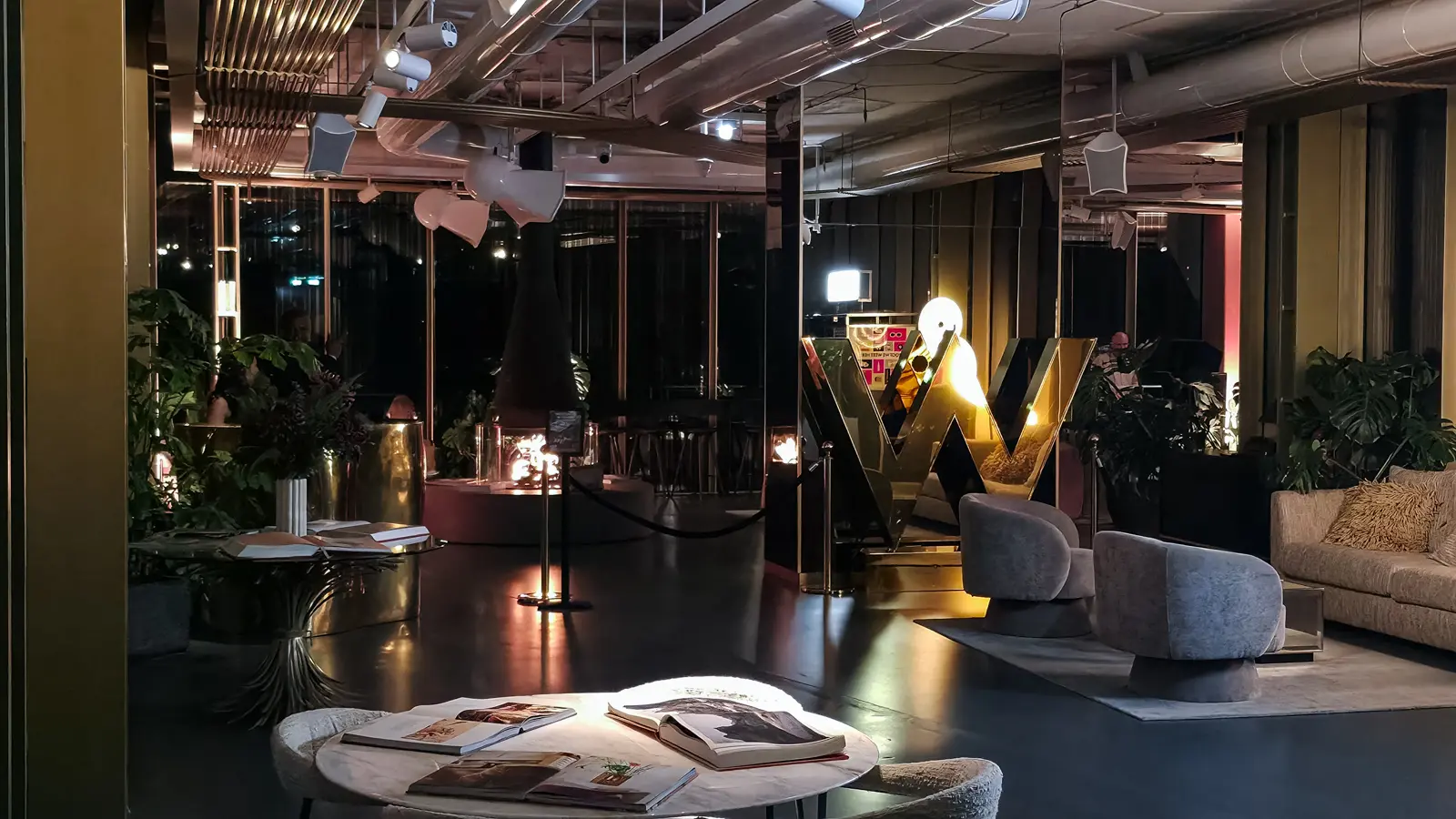 The W Lounge after midnight at the W Amsterdam, with the gold mirrored W lit under a spotlight and lamps low across the seating