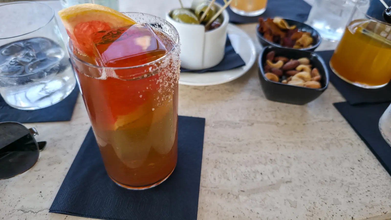 The Spice Courier at the W Lounge, W Amsterdam, a tall cocktail with a grapefruit slice and a salted rim on a dark napkin