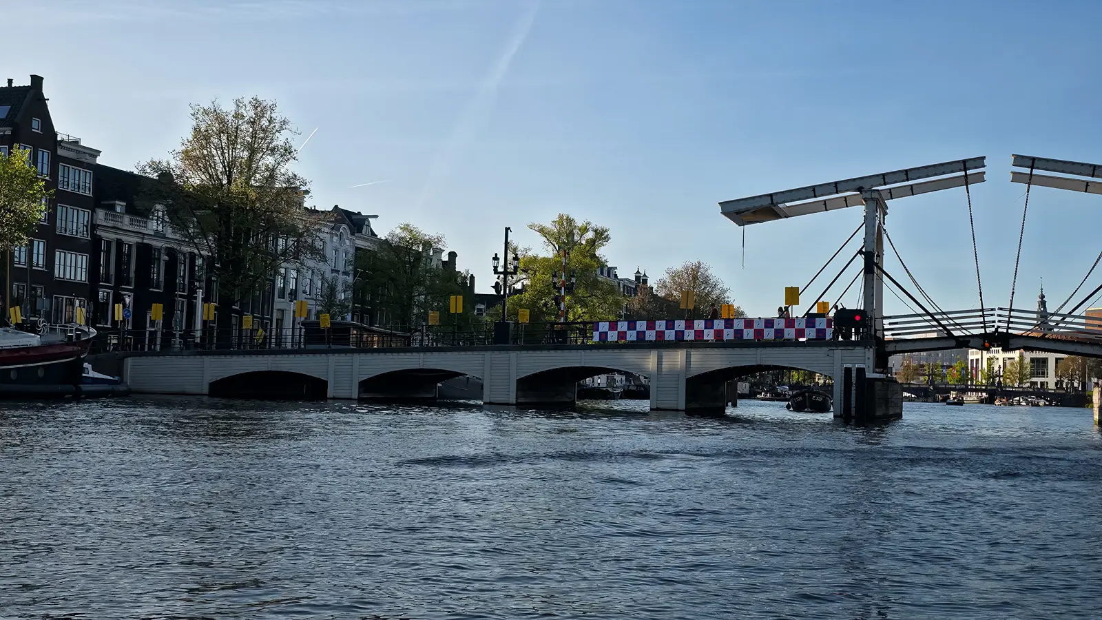 The Magere Brug over the Amstel in Amsterdam with its white wooden bascule section raised and a red light showing