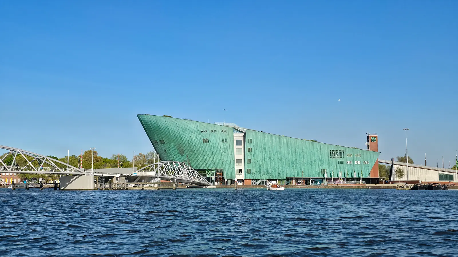 NEMO Science Museum in Amsterdam, the green copper building rising from the water like a ship's prow, with a footbridge in front