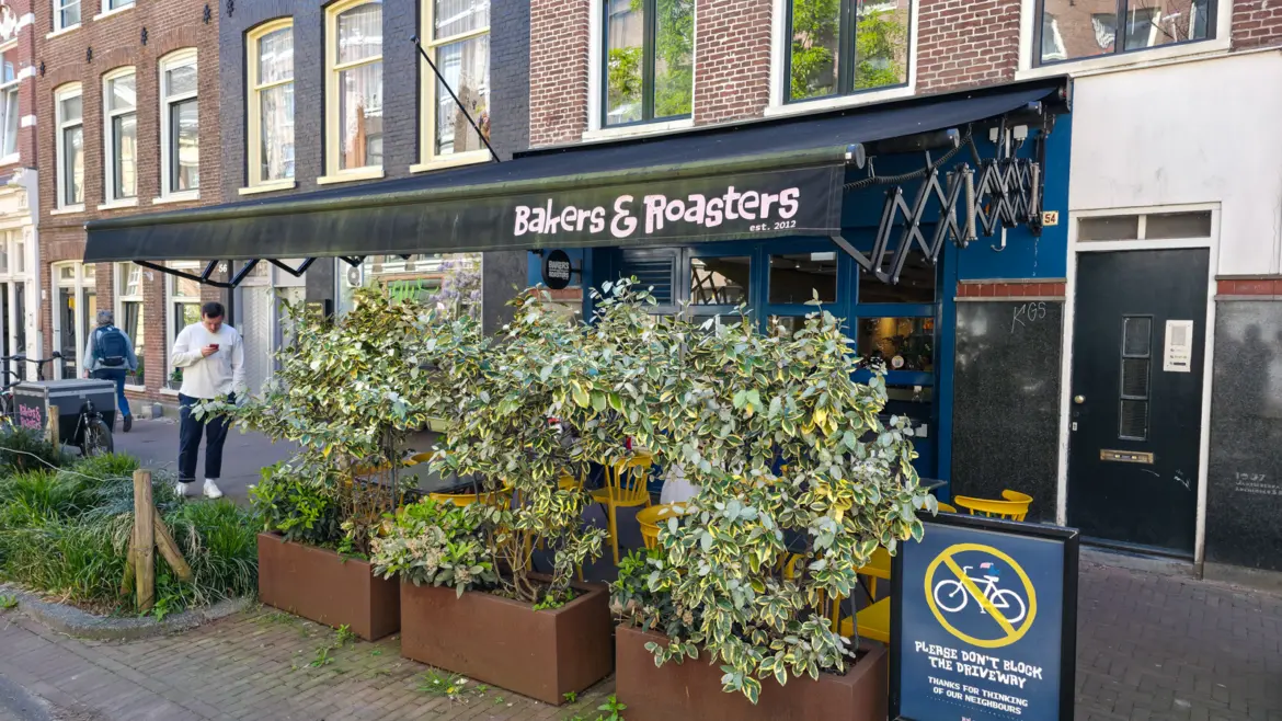 The black Bakers & Roasters awning reading est. 2012 above the blue frontage and yellow pavement chairs on Eerste Jacob van Campenstraat, De Pijp, Amsterdam