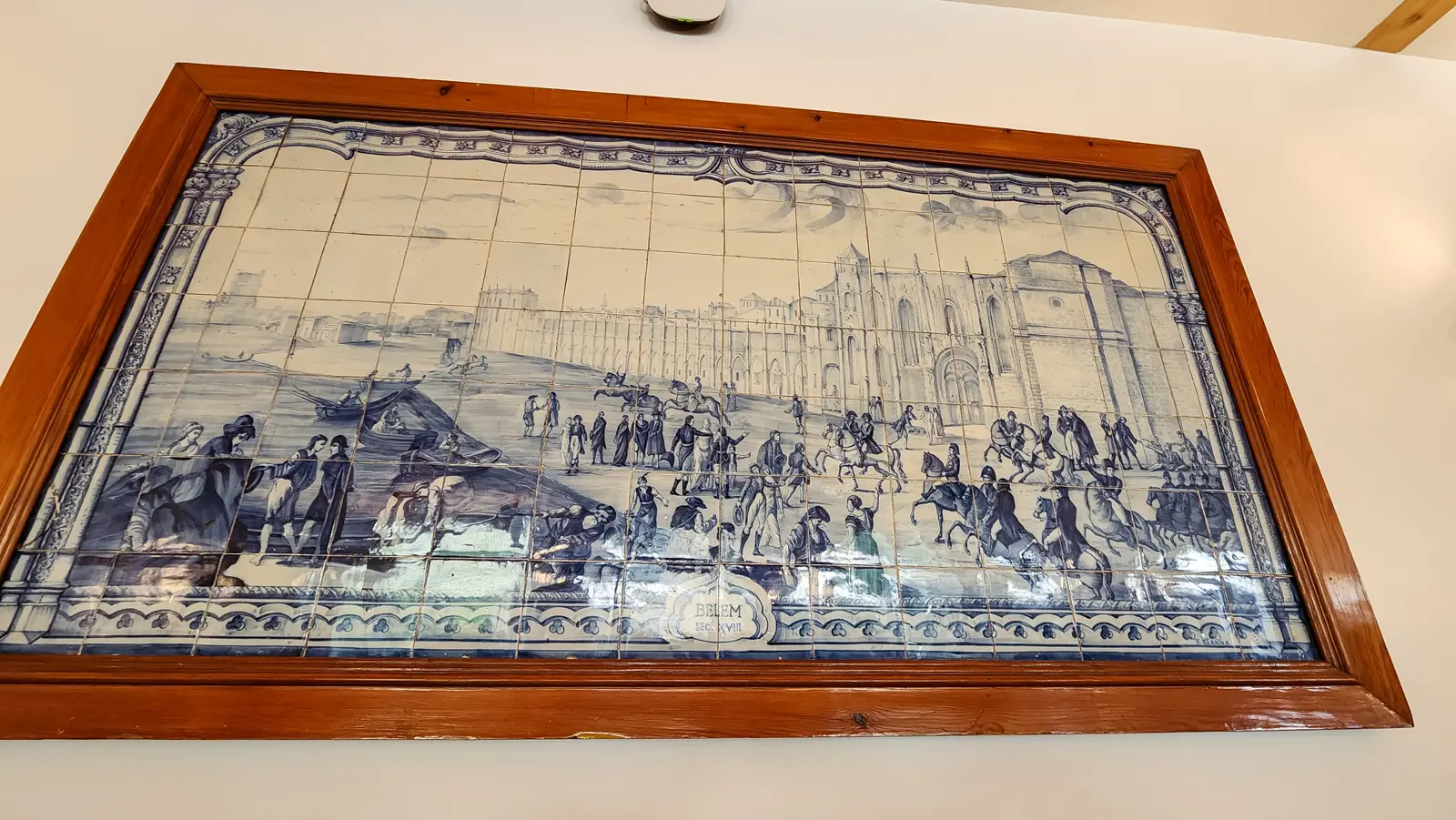 Framed eighteenth-century azulejo panel showing Belém and its monastery, hanging in a pastry shop in Belém, Portugal