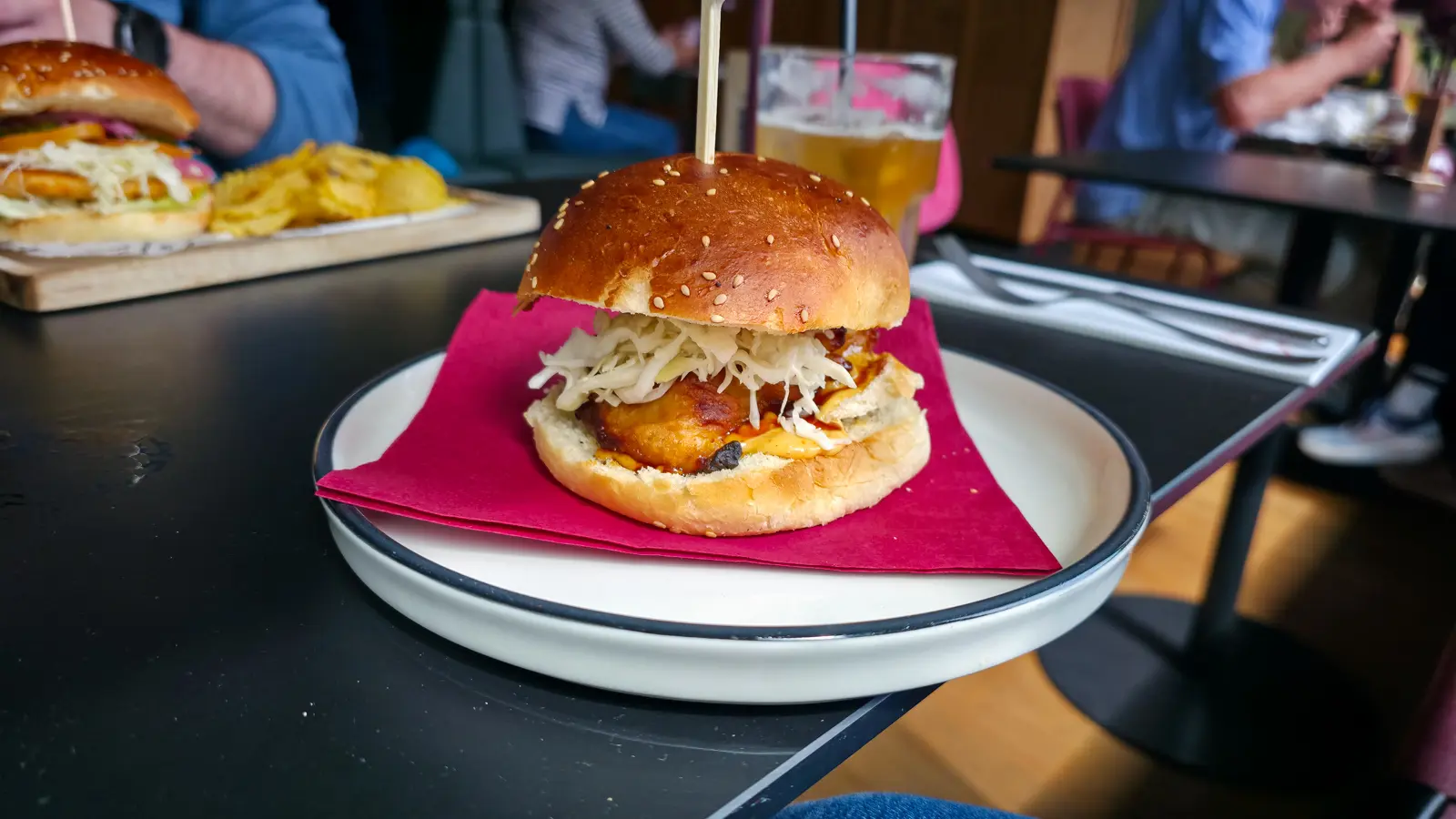 Katsu chicken burger on a brioche bun with coleslaw and sauce, on a white plate at Bistro Vincent, Van Gogh Museum, Amsterdam
