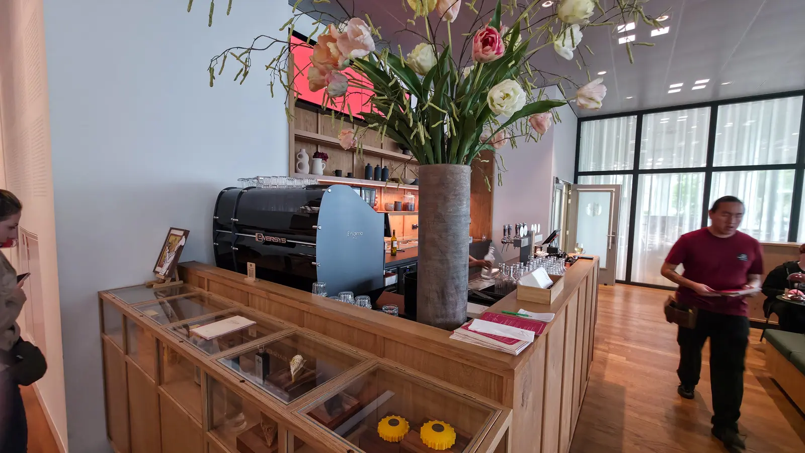 Service counter at Bistro Vincent, Van Gogh Museum, Amsterdam, with a coffee machine, a tall vase of tulips and glass display cabinets