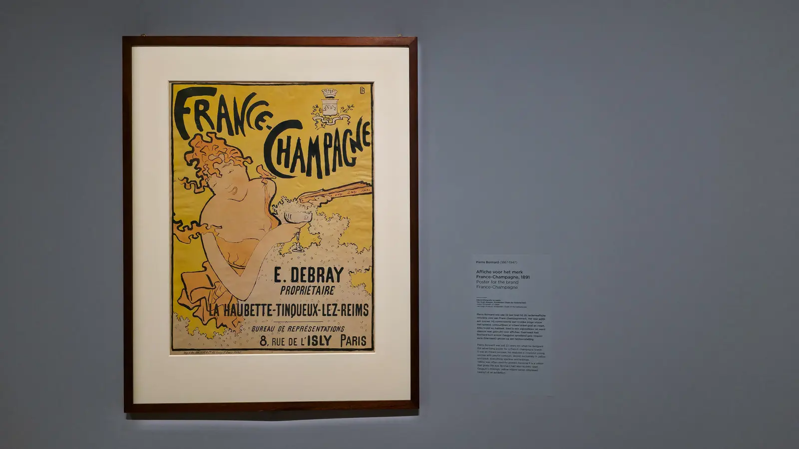 Pierre Bonnard's France-Champagne poster (1891), a laughing woman with a champagne glass drawn in yellow and black, framed at the Van Gogh Museum