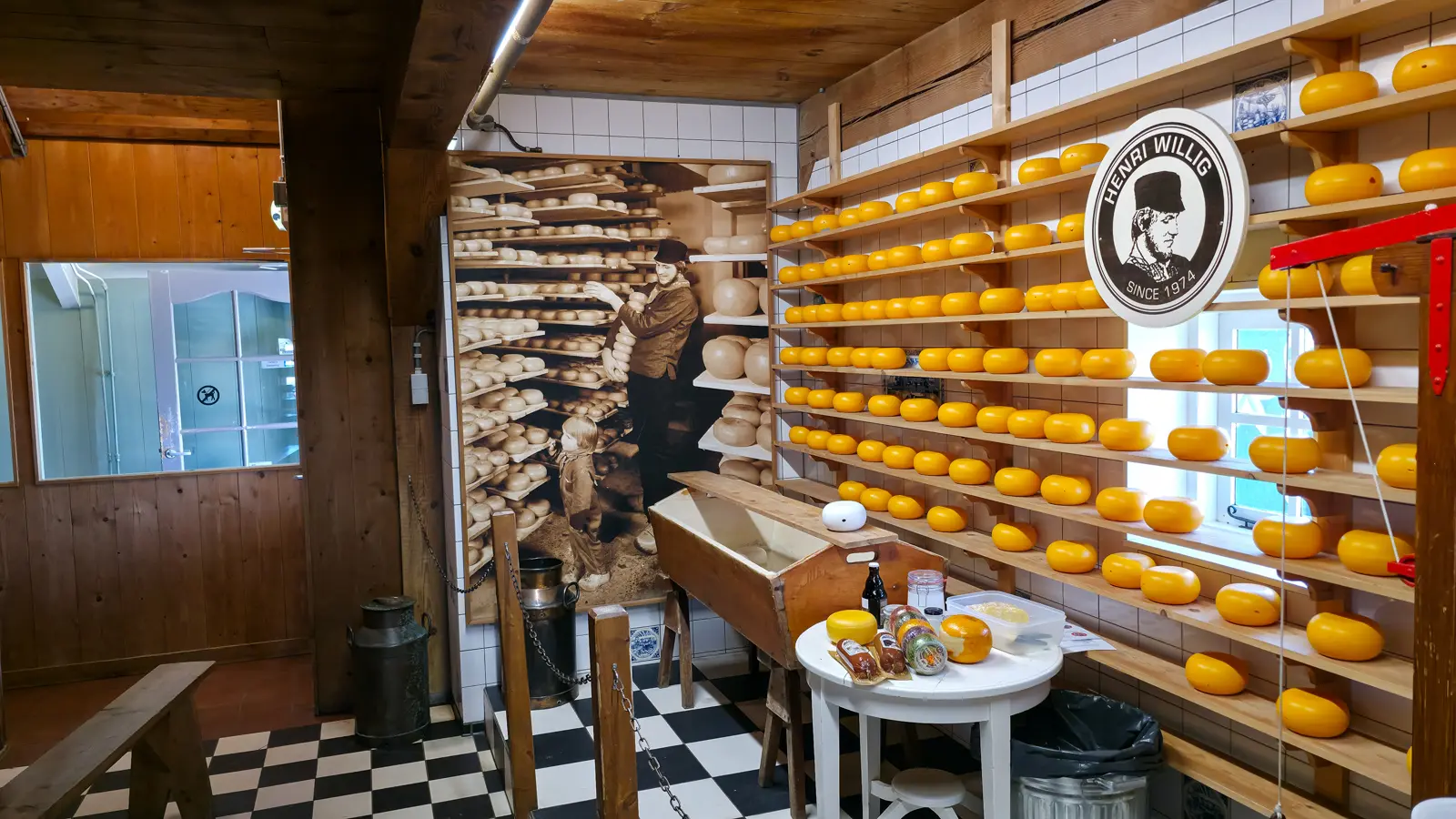 Demonstration room at Catharina Hoeve with chequerboard floor, a wooden trough and racked cheese wheels, Zaanse Schans
