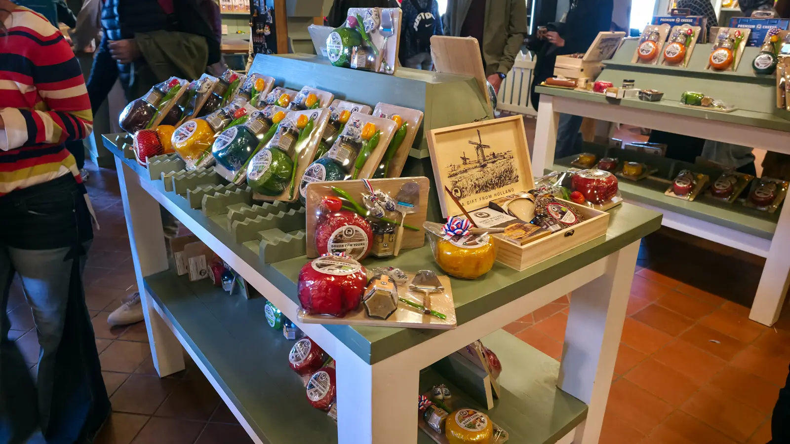 Gift table in the Catharina Hoeve shop with wax-sealed cheeses, wooden boards, Delft-handled slicers and a Gift from Holland box