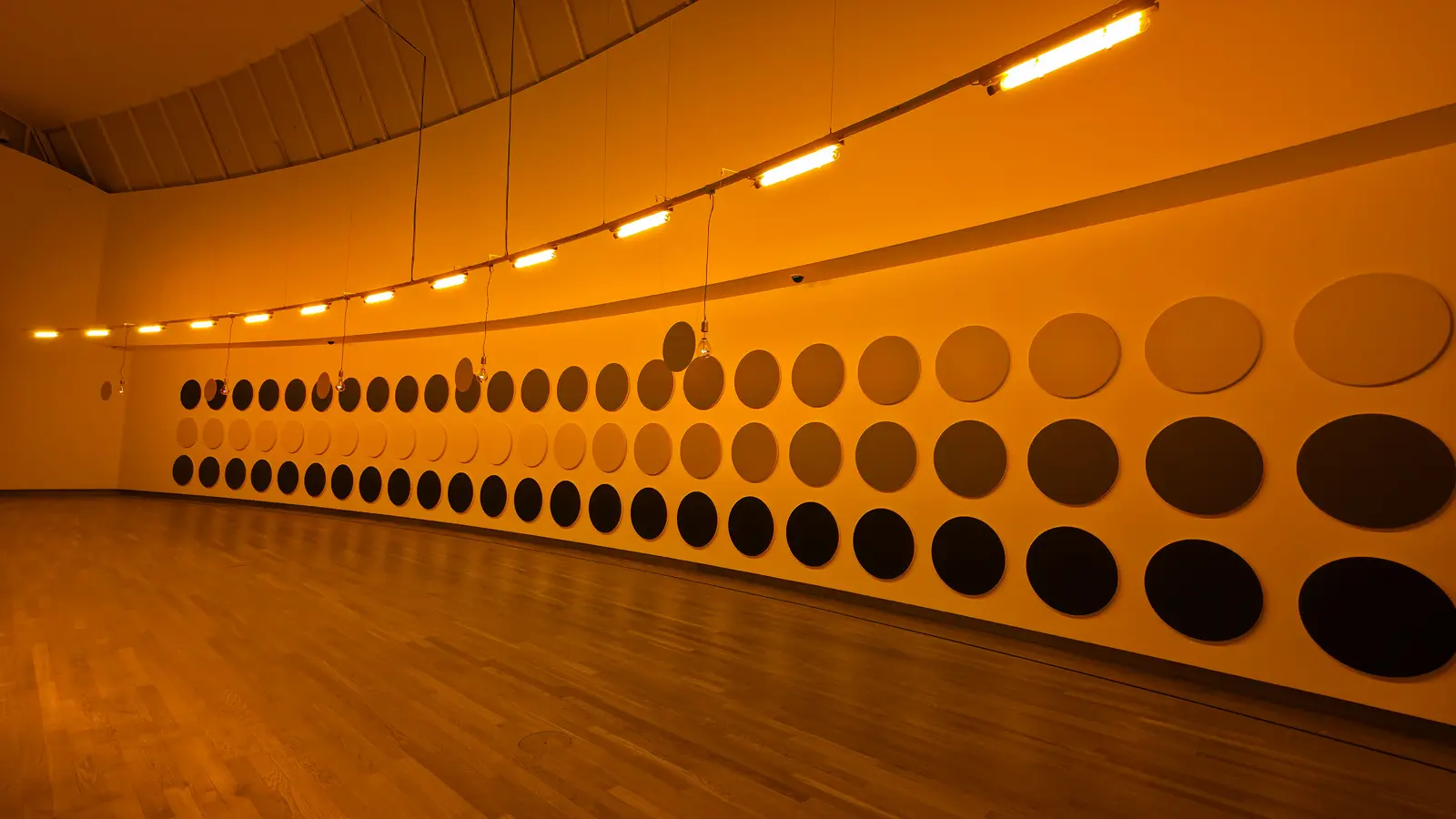 Olafur Eliasson's light installation, a row of yellow mono-frequency lamps above a curved wall of circles reading in shades of yellow, grey and black, at the Van Gogh Museum
