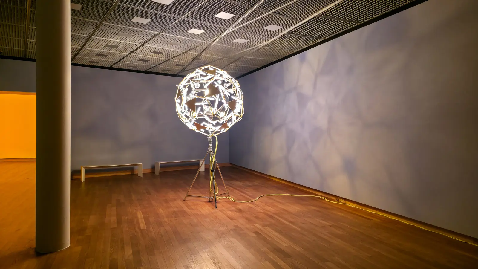 Olafur Eliasson's Who is afraid yellow flower ball (2006), a glowing ball of lamps and mirrors on a tripod casting a web of shadows on cool grey walls, at the Van Gogh Museum