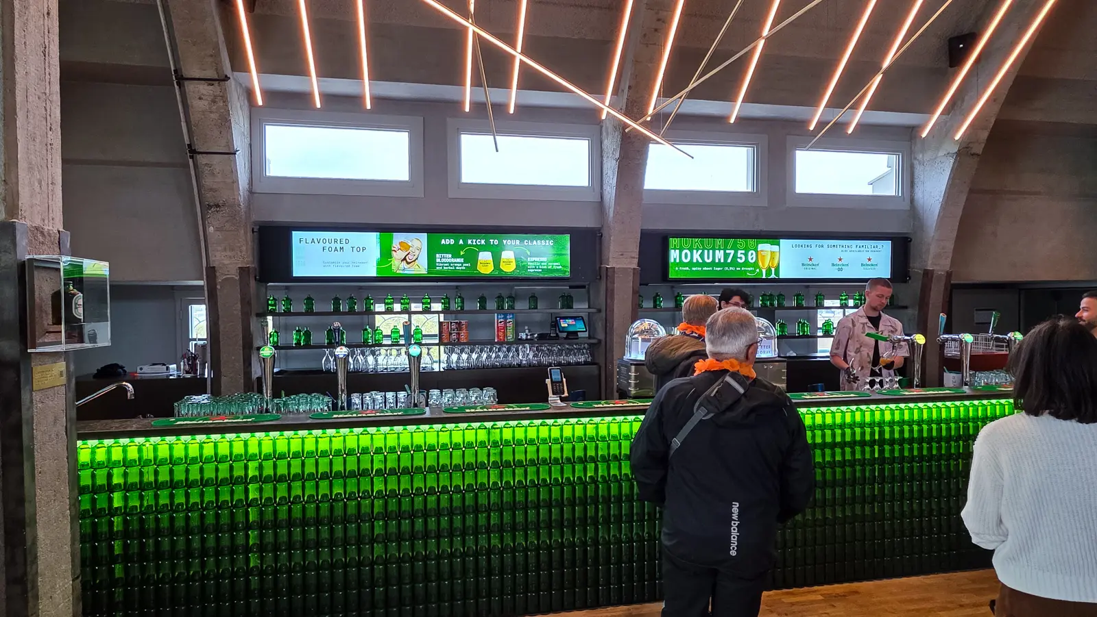 Screens above the bar at the Heineken Experience, Amsterdam, advertising Mokum750 and flavoured foam tops in blood orange and espresso
