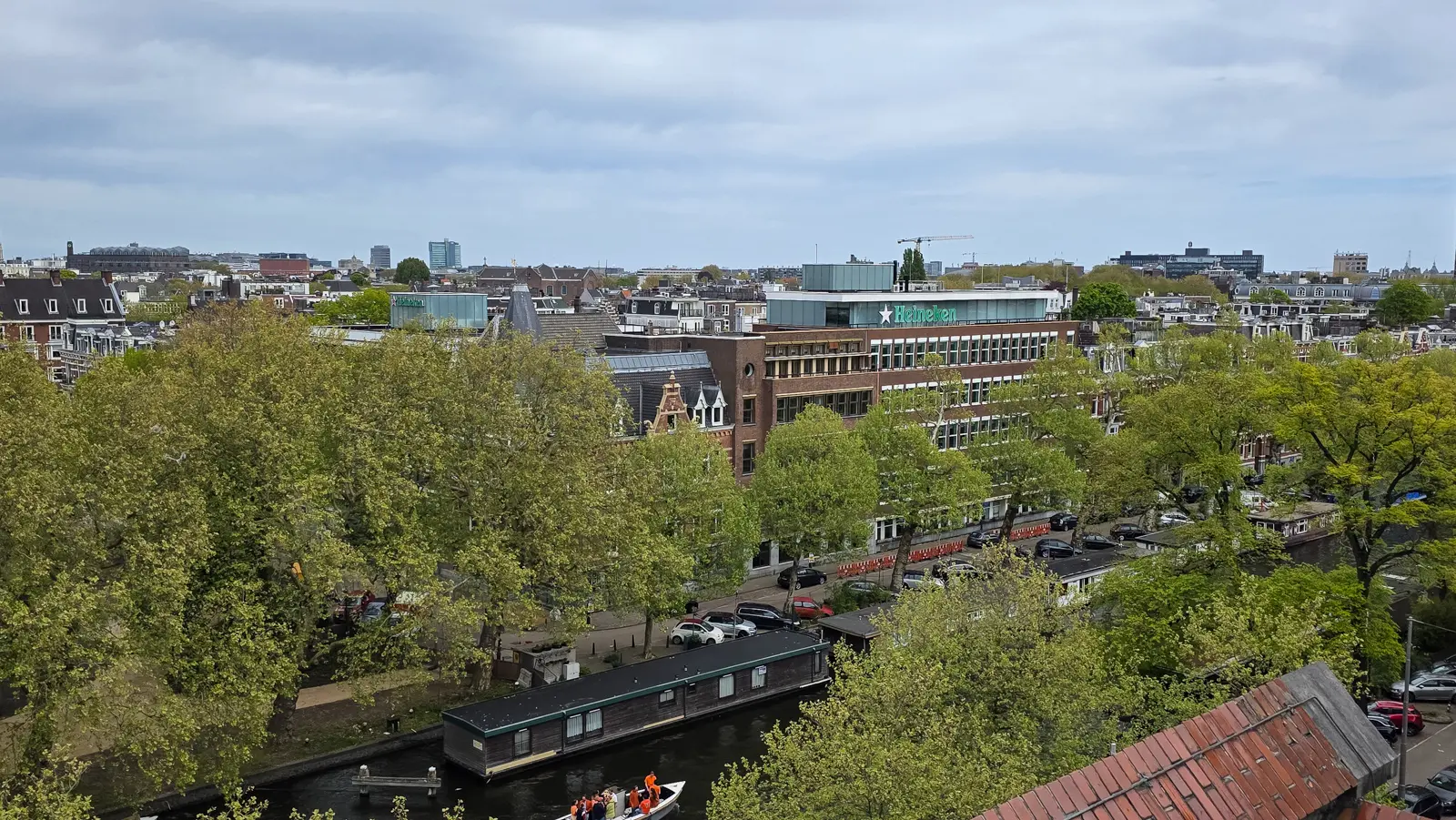 View over Amsterdam rooftops and the Singelgracht from the Heineken rooftop terrace, towards a modern block carrying the Heineken name