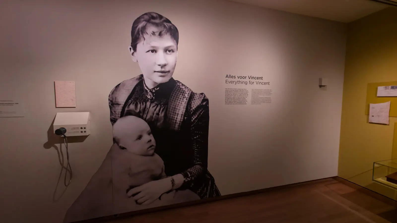 A wall-height photograph of Jo van Gogh-Bonger holding her baby son Vincent Willem, beside the Everything for Vincent panel at the Van Gogh Museum, Amsterdam