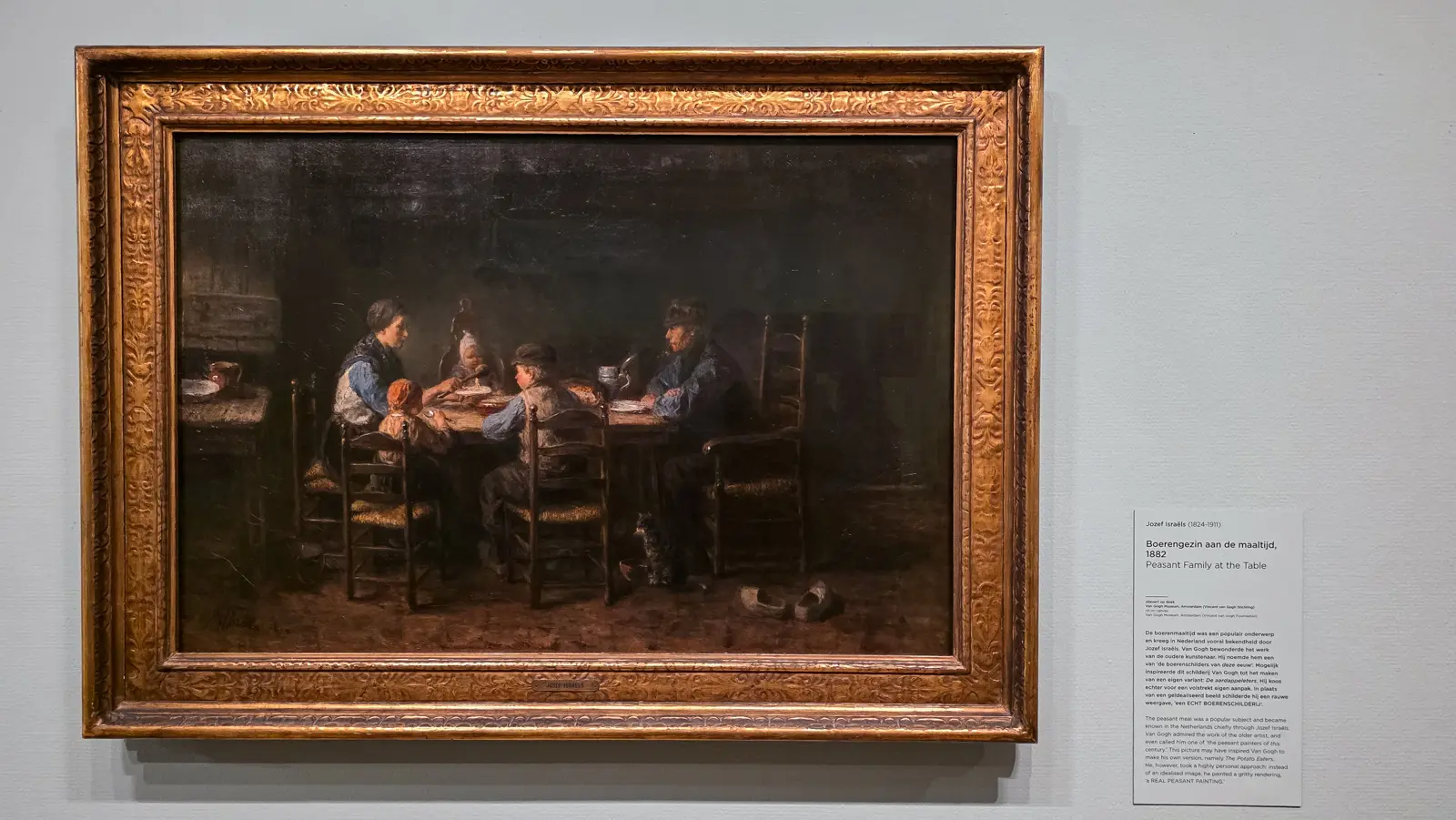 Peasant Family at the Table by Jozef Israels, 1882, a family round a table with a child, a dog and wooden shoes on the floor, Van Gogh Museum, Amsterdam