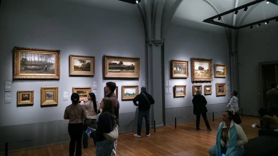 Visitors in the 1800 to 1900 galleries at the Rijksmuseum, Amsterdam, looking at Hague School landscapes hung two rows deep