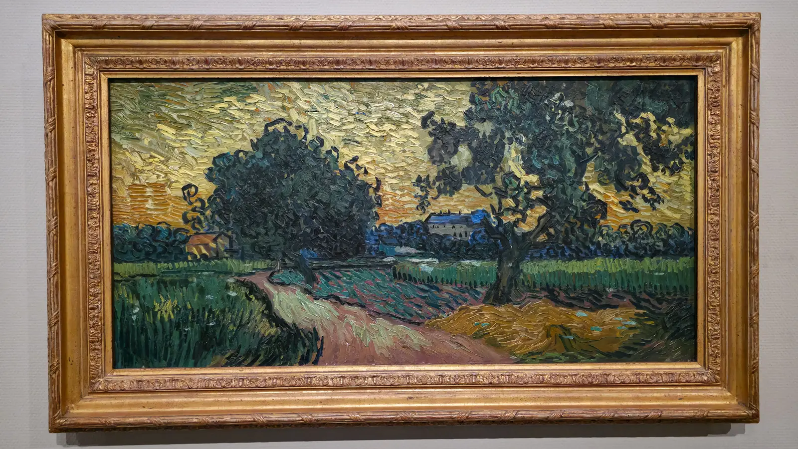 Van Gogh's Landscape at Twilight (1890), a wide double-square canvas with a path through green fields toward the chateau of Auvers under a thick orange and yellow sky