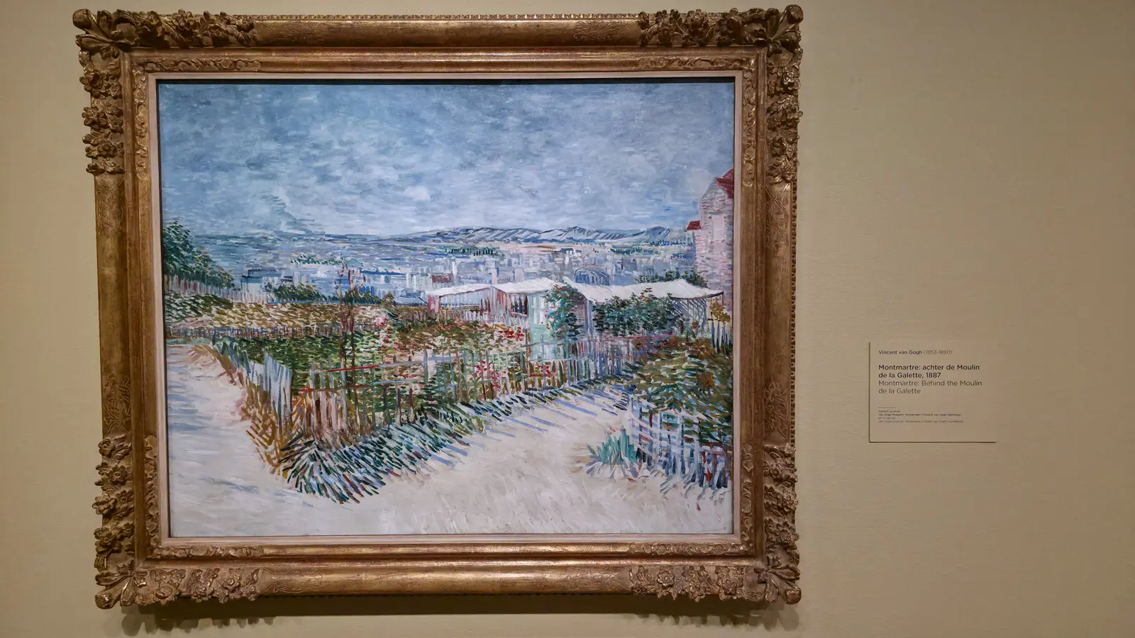 Van Gogh's Montmartre: Behind the Moulin de la Galette (1887), a white path with blue shadows between fenced green-and-red gardens with Paris beyond, Van Gogh Museum