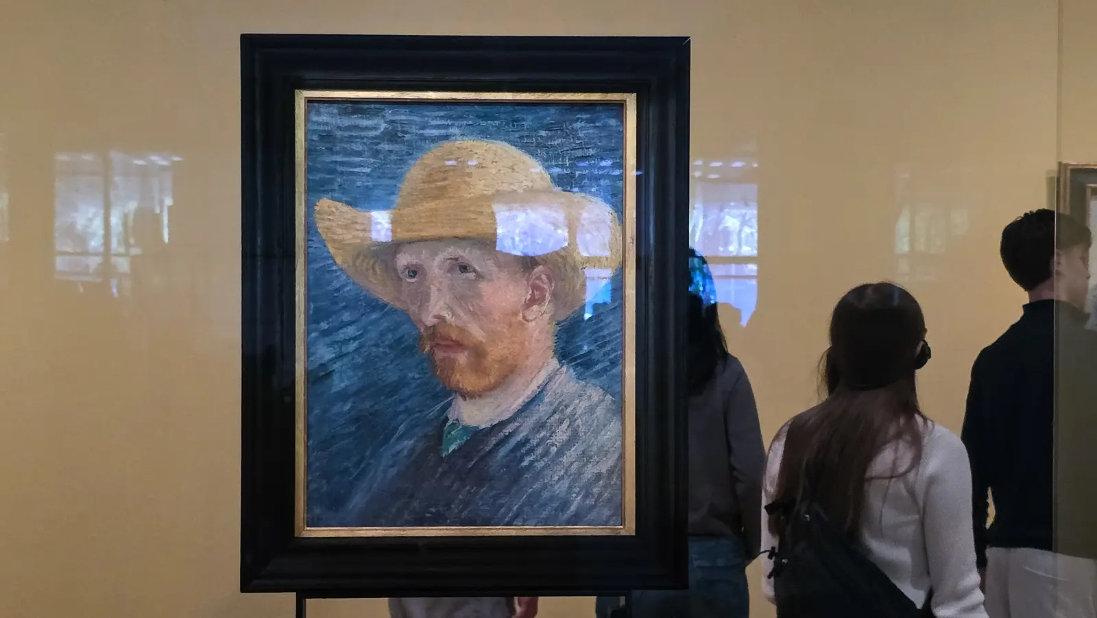Self-Portrait with Straw Hat, July to August 1887, in a freestanding glass case with reflections across the surface, Van Gogh Museum