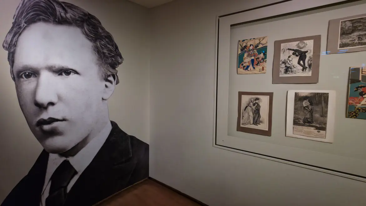 A wall-height photograph of Vincent van Gogh beside a glass case of Japanese woodcut prints at the Van Gogh Museum, Amsterdam