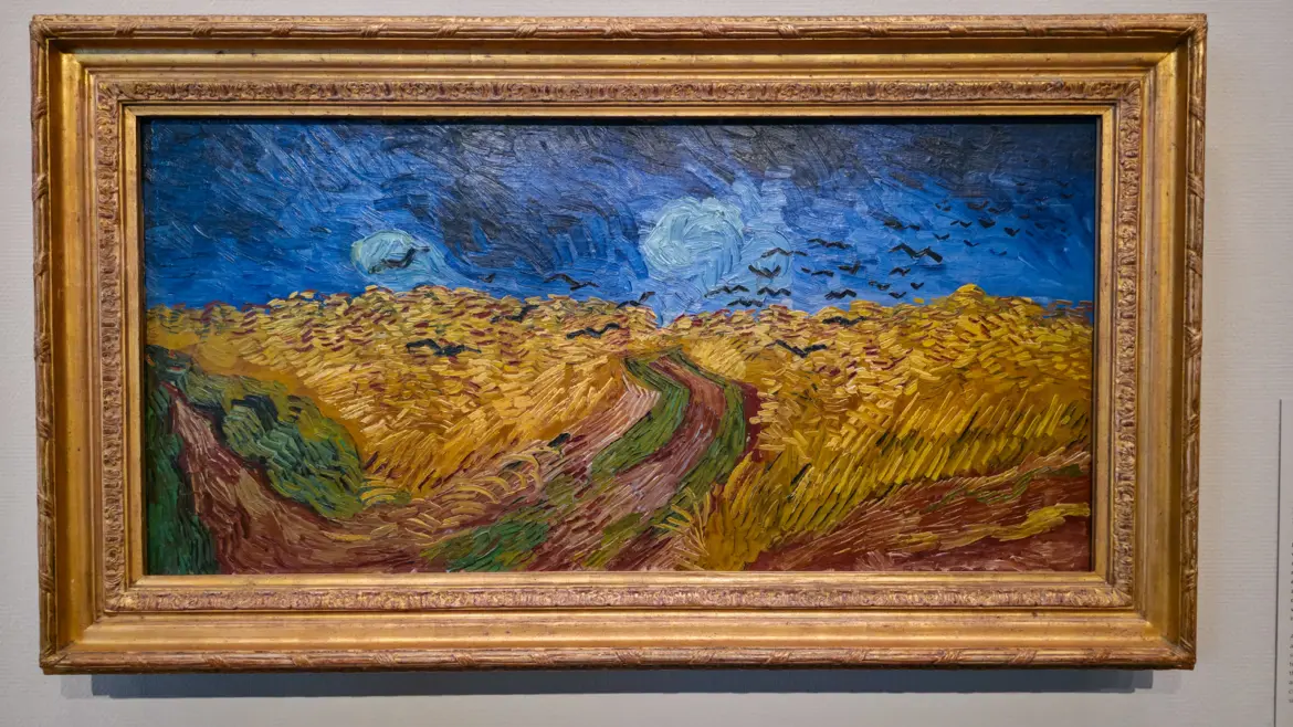 Van Gogh's Wheatfield with Crows (1890), a dark blue and black sky over yellow wheat with a red dirt path through the middle and crows in quick black strokes, Van Gogh Museum