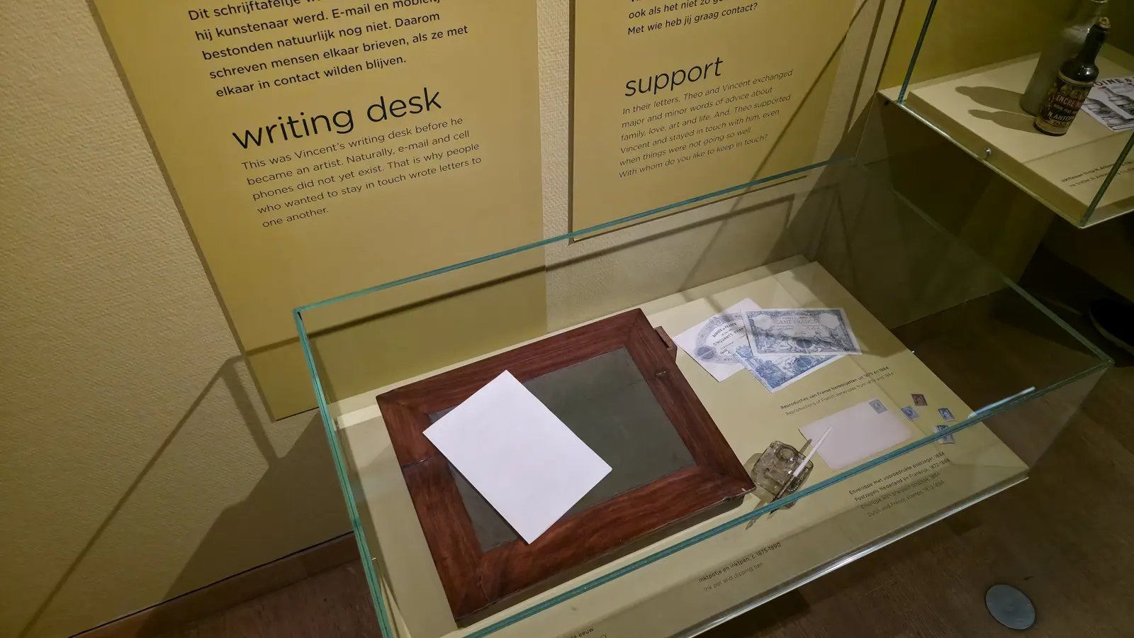 Vincent van Gogh's sloped wooden writing desk in a display case, with an ink pot, a dipping pen, an envelope and reproduction French banknotes, Van Gogh Museum, Amsterdam