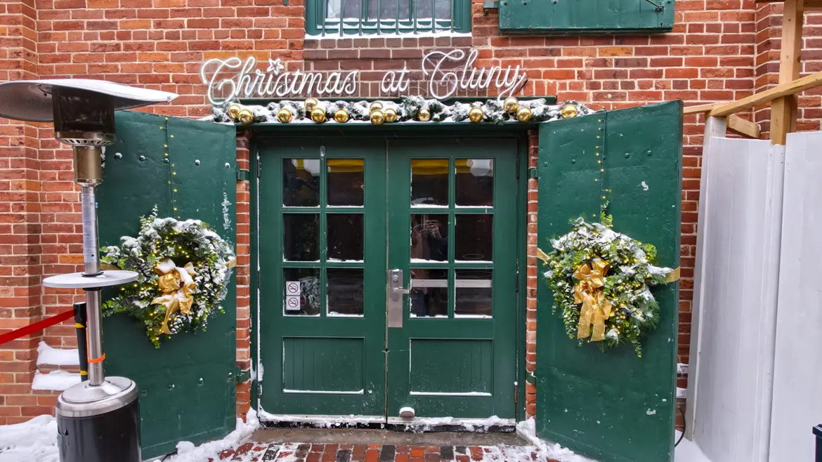 Cluny's green double doors with gold baubles, wreaths and a Christmas at Cluny sign, Distillery District, Toronto